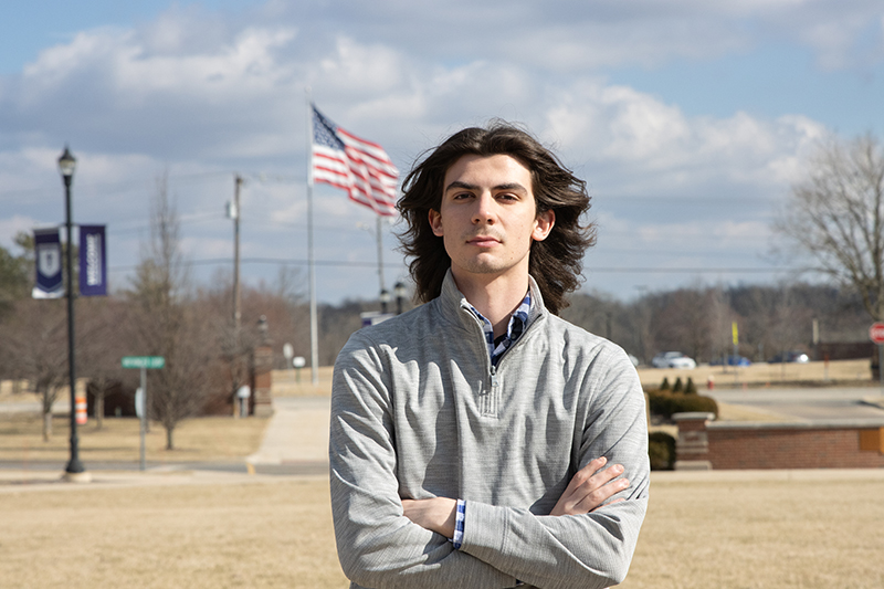 Sam Maurer standing in front of American flag