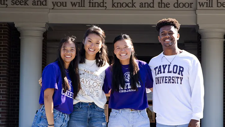 Group of international students with their arms around each other smile at the camera