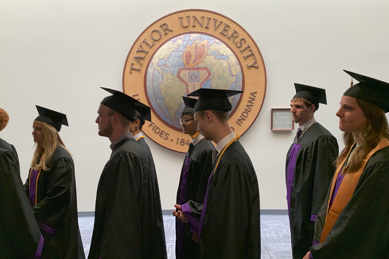 graduates walking past Taylor's presidential seal
