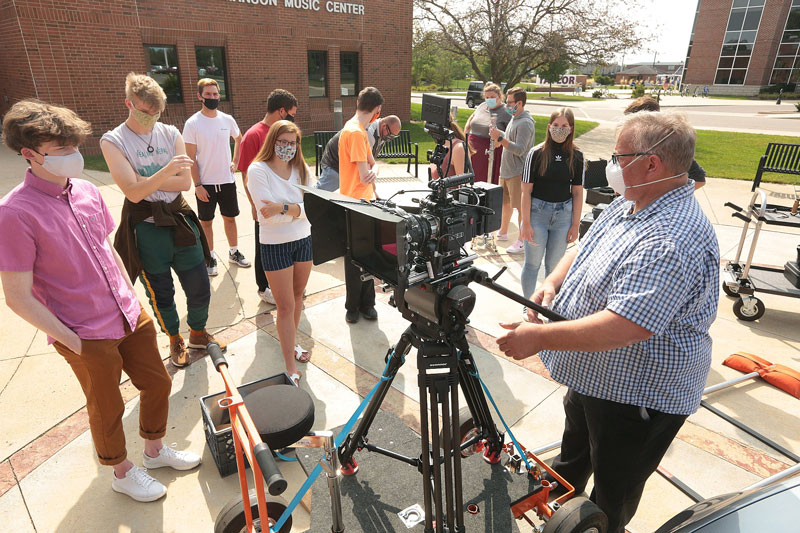 Professor operating a camera outside while students observe