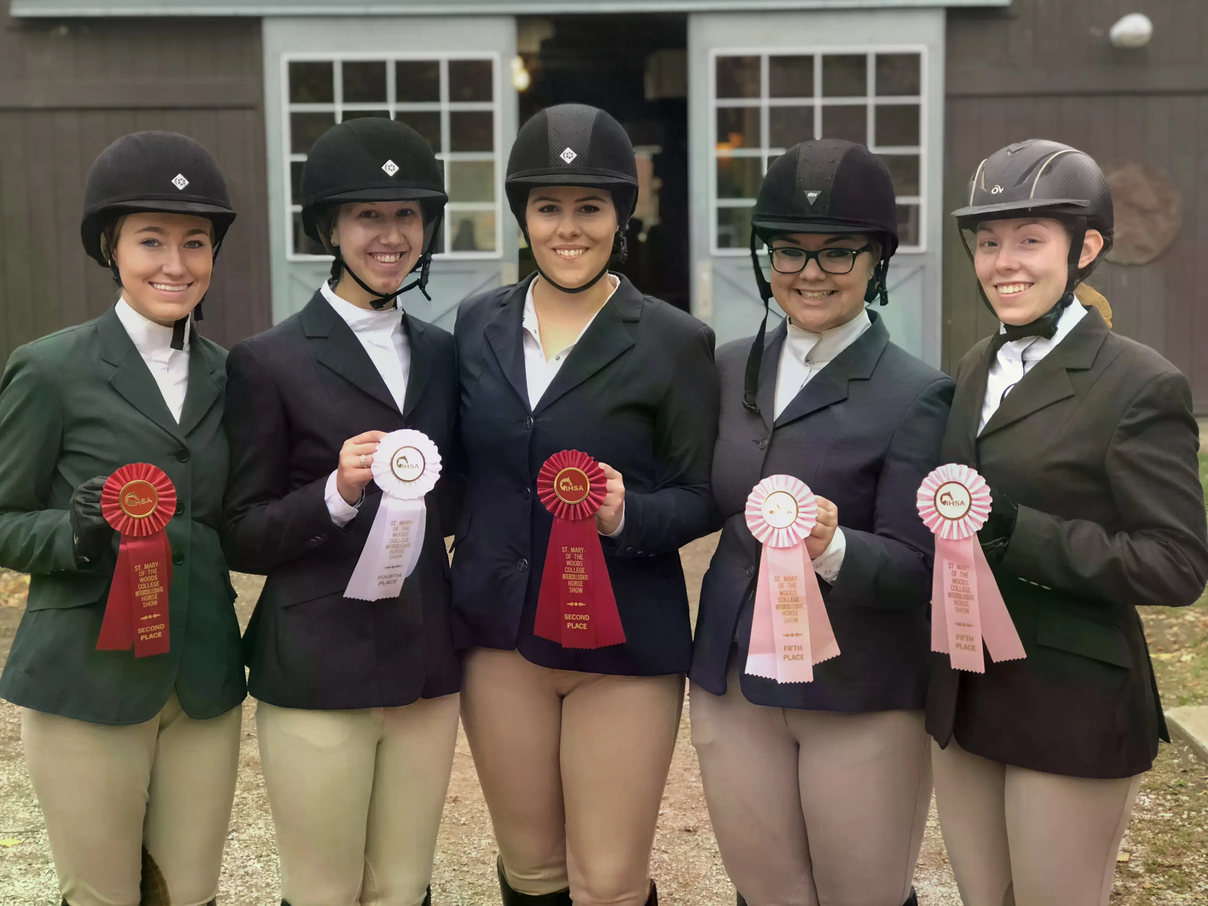 The Equestrian Team outside holding their ribbons with helmets on