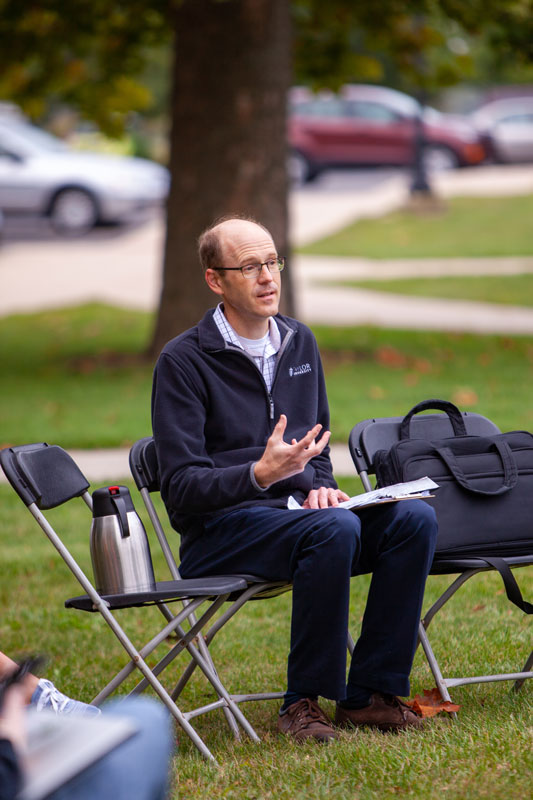 Professor teaching from a chair outside