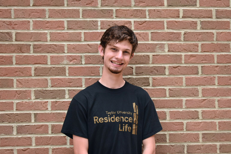 male student in front of brick wall