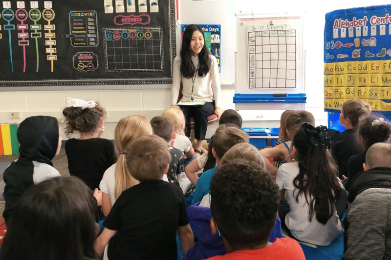 A Taylor student standing in front of a class of children