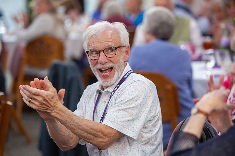 older man clapping at reunion dinner