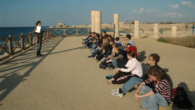 Taylor students sitting on a pier, listening to a professor