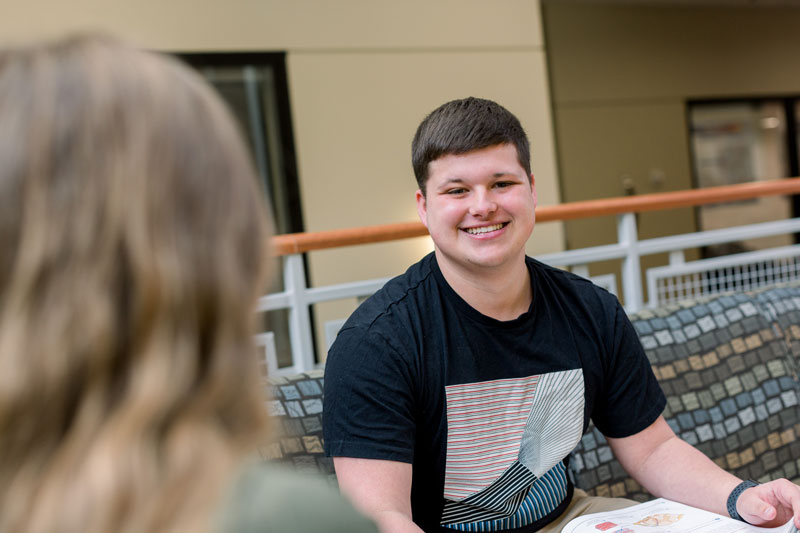 Student smiling and studying Legal Studies in the Euler Atrium