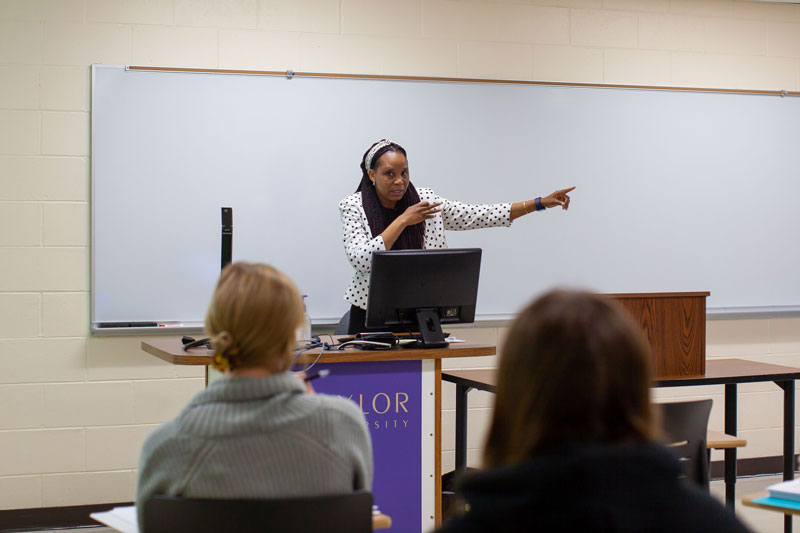 Professor pointing while teaching behind lectern