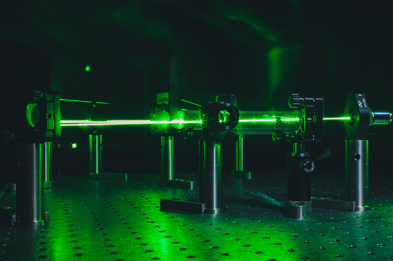 A green laser being reflected in a dark room