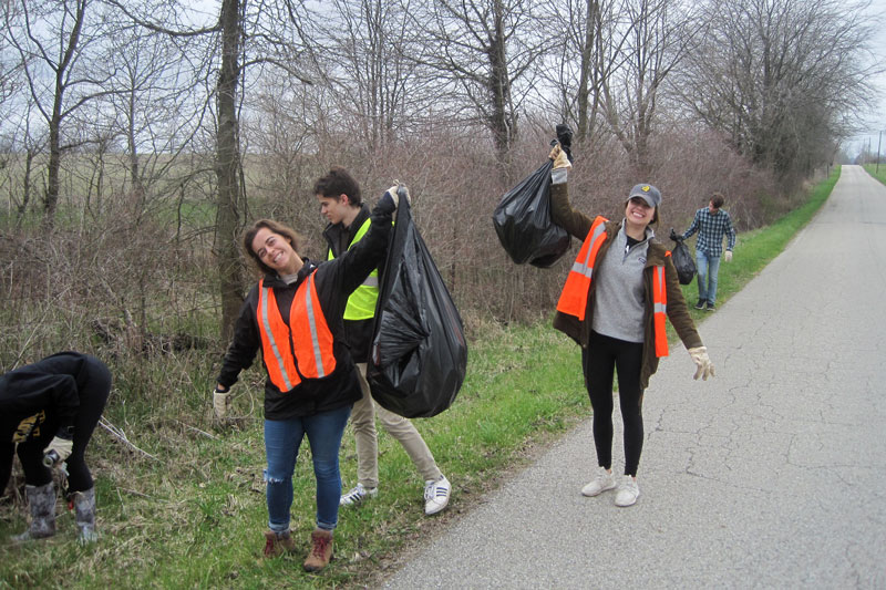Students picking up trash along the side of the road