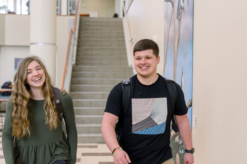 Two students walking in the Euler Atrium and smiling