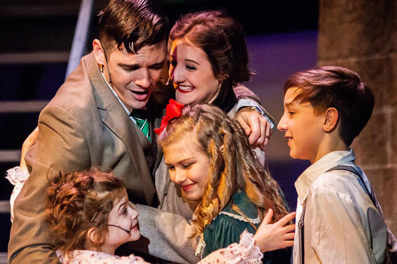 Leah Perry hugging a man and children in a play