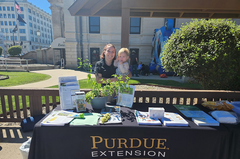 Jessica Outcalt stand behind Purdue table