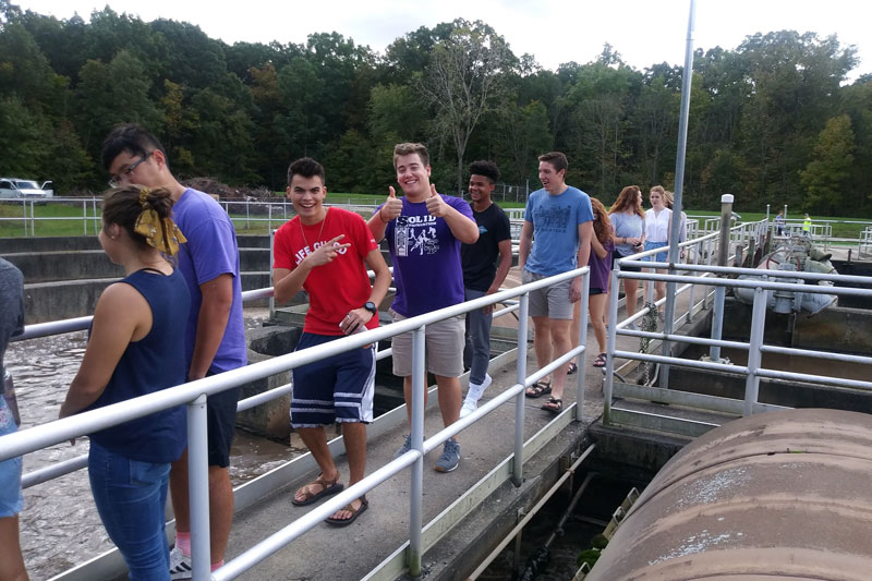 Students standing on a pier at a lake
