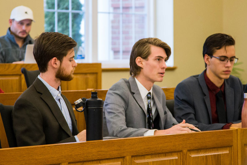 A group of students in suits debating in Ethics Bowl
