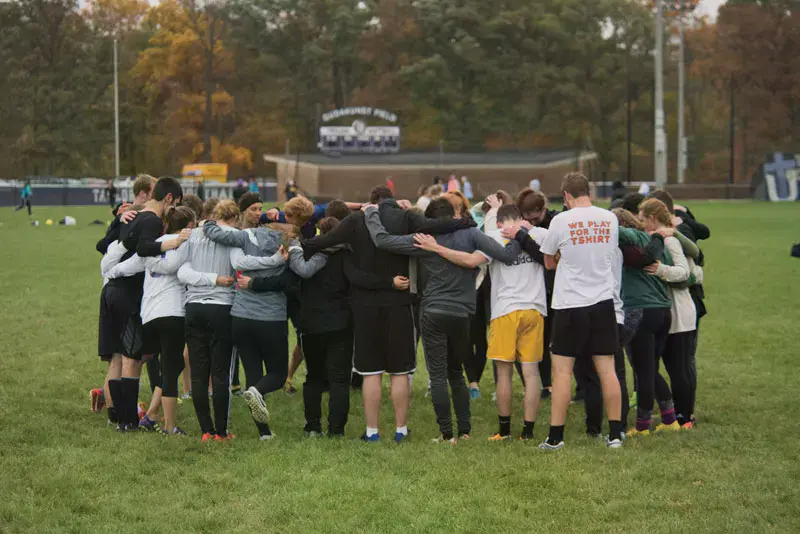 Students in a circle praying after an intramural game