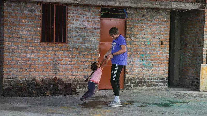 A male student swinging a child in Nepal