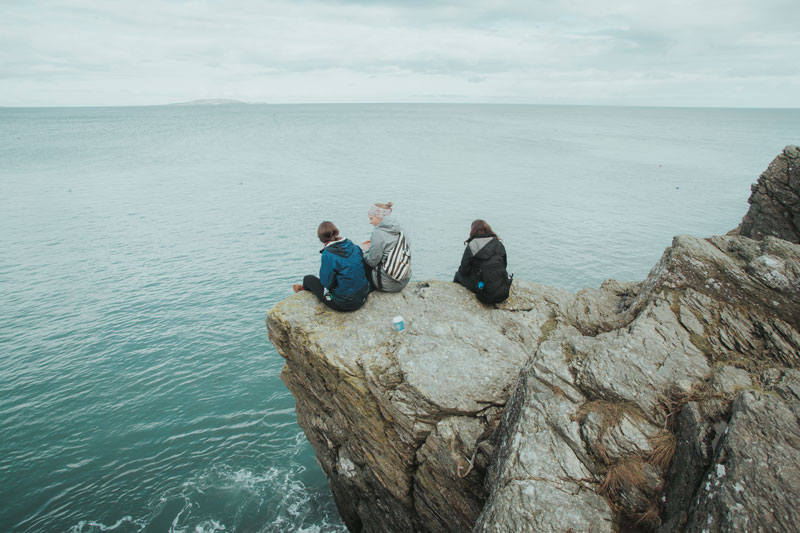 Students sitting on a cliffside over the ocean