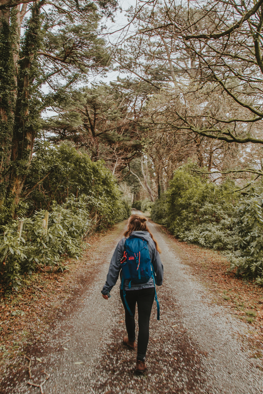 student walks down a road into the woods
