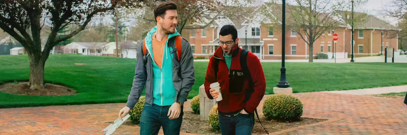 Two Male Students Talking as they Walk Across Campus.