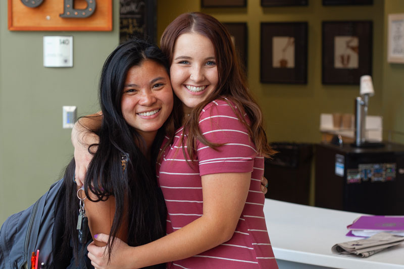 Two students hugging in front of the Jumping Bean