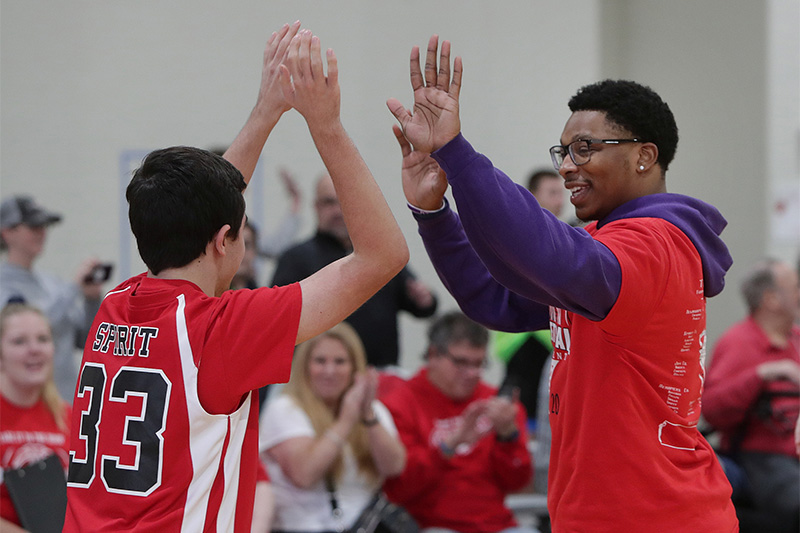 student and athlete give each other high fives