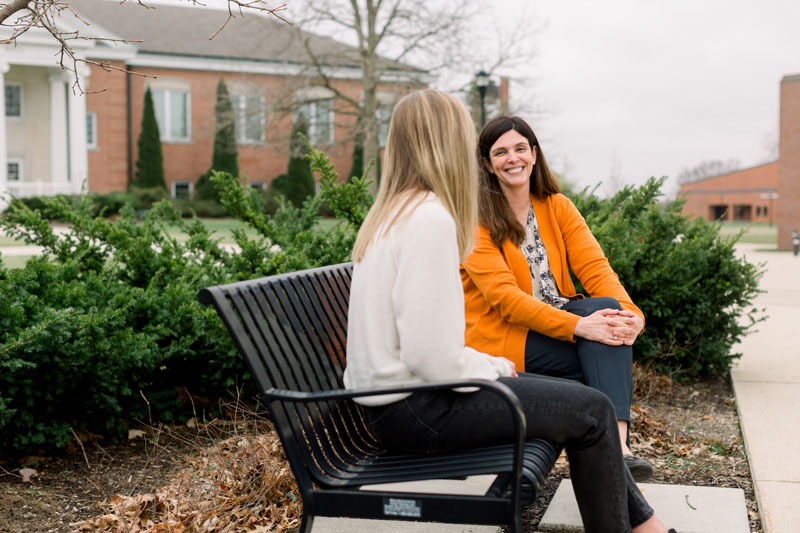 Two students talking on a bench outside Ayres Hall