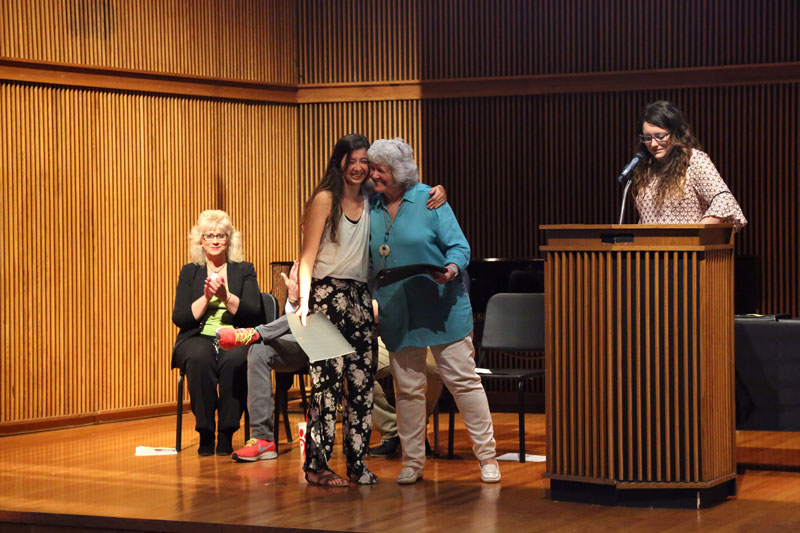 A student hugging a professor onstage in the Butz-Carruth Recital Hall