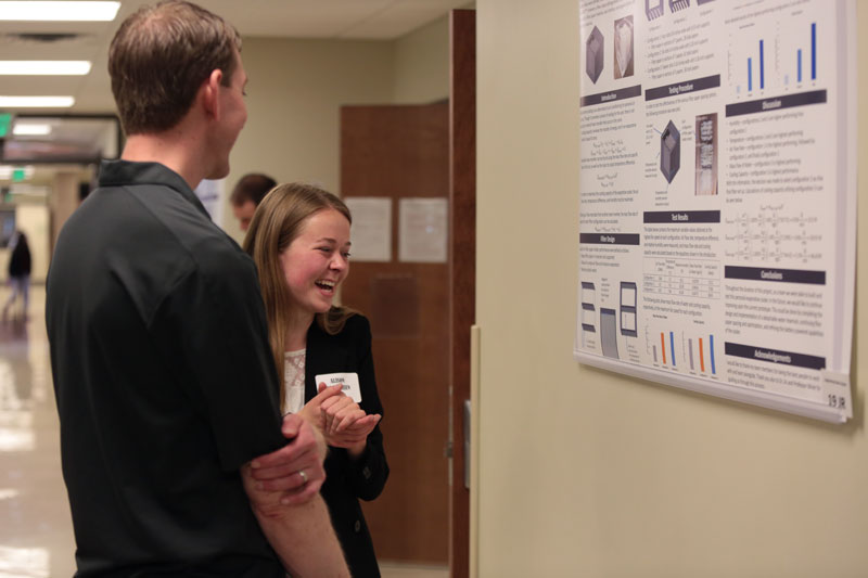 Student laughing while presenting a poster on her research