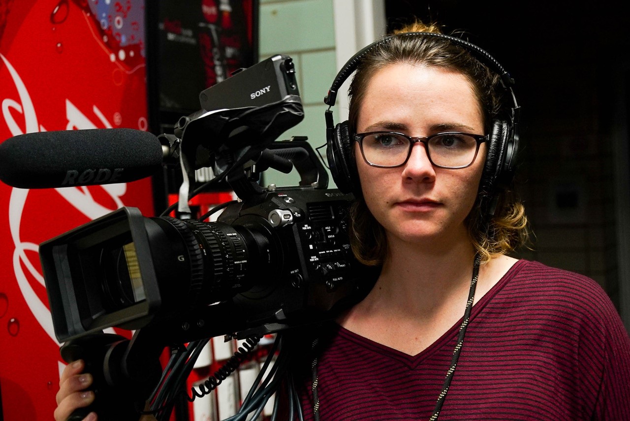 female student holding film camera wearing headphones