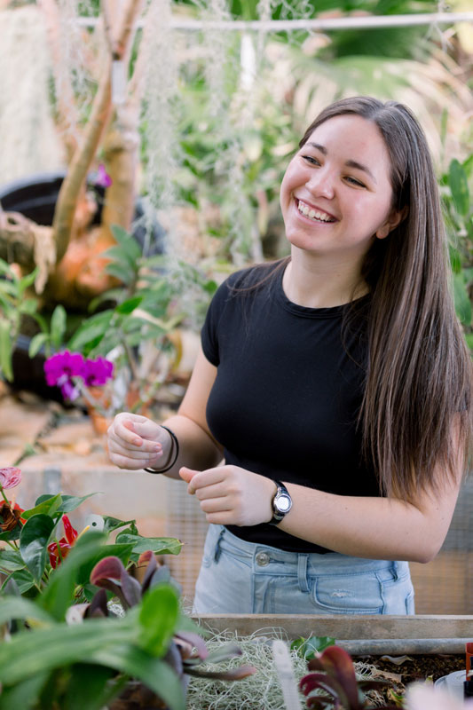 female student with orchids in greenhouse