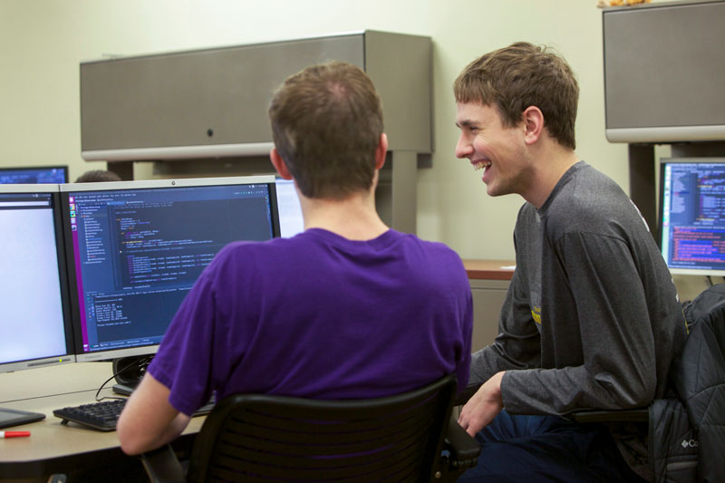 Two students laughing while coding