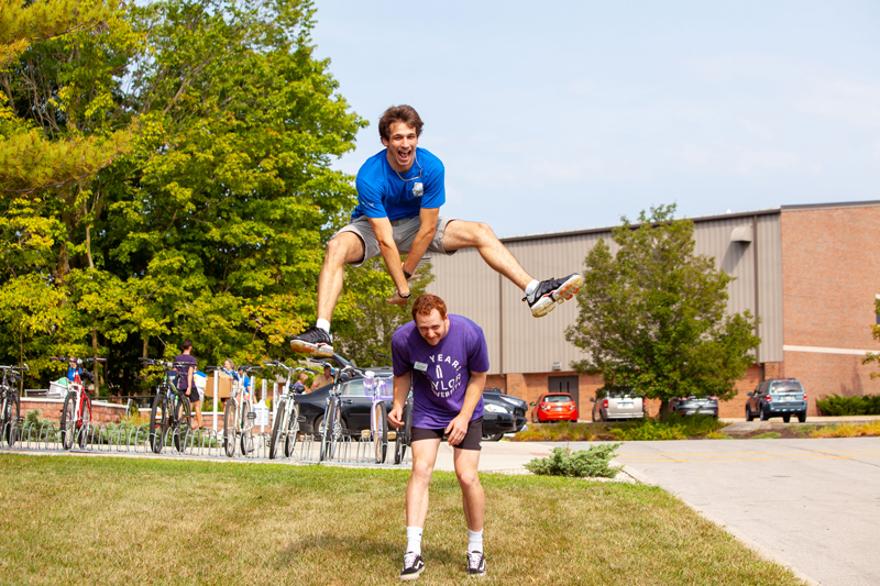 A student jumping over another student outside Bergwall Hall