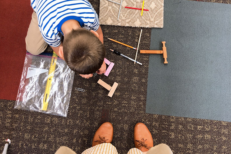 A teacher looking down at a child playing on the floor