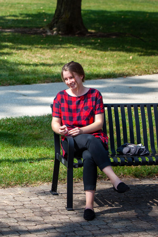 A student smiling on a bench outside