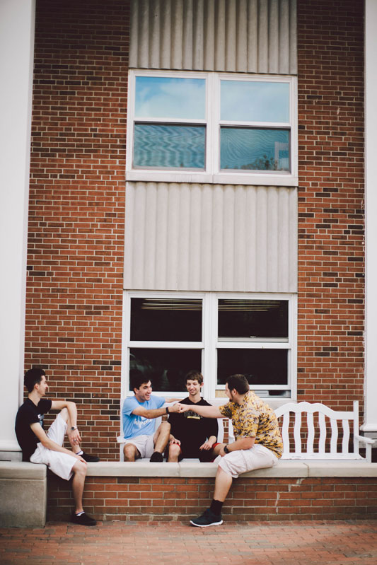 group of students sitting on a bench outside a dorm