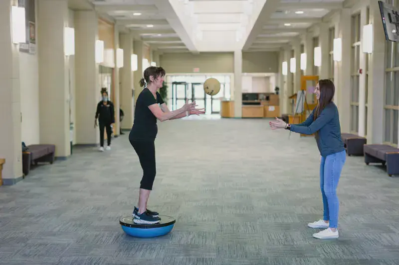 Students using balance board and throwing therapy ball