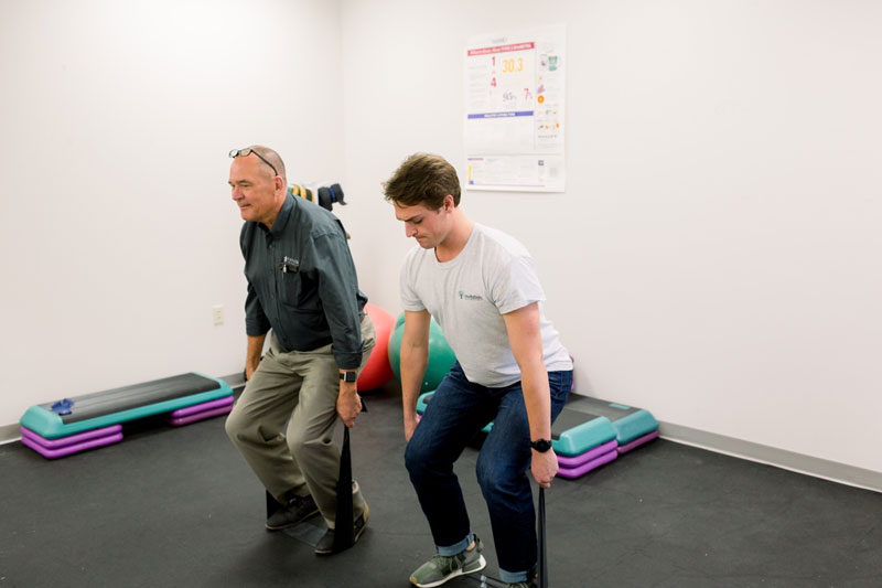 A student doing a mobility exercise with an older man