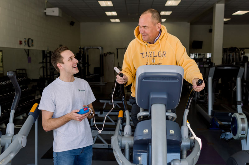 Taylor student working with a man on an elliptical