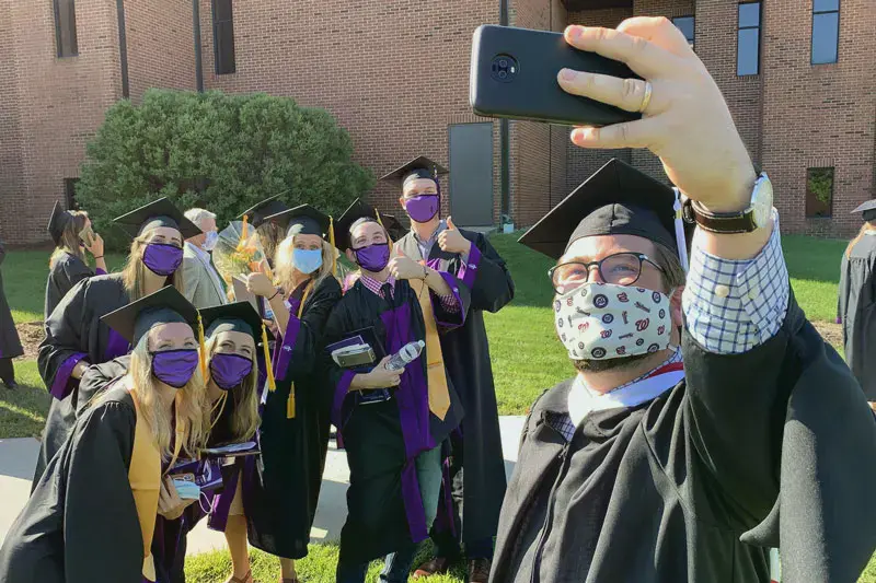 Masked students taking a selfie at 2020 commencement