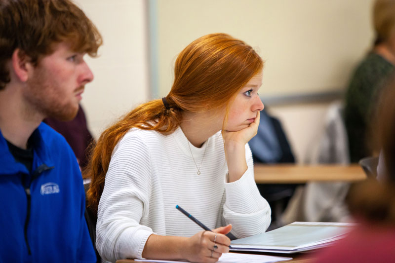 Female student listening attentively and taking notes