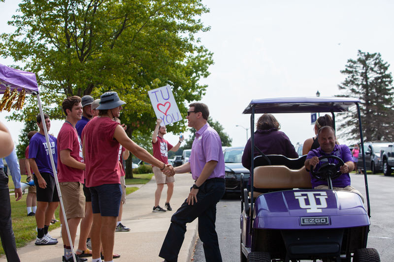 Dr Michael Lindsay shaking hands with a student next to a TU golf cart