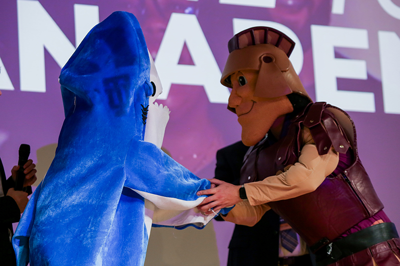 Trojan mascot shaking hands with shark mascot