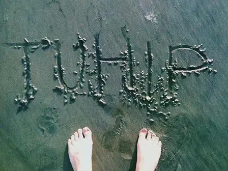 Female student's feet next to Taylor university Hollywood Internship Program written into sand