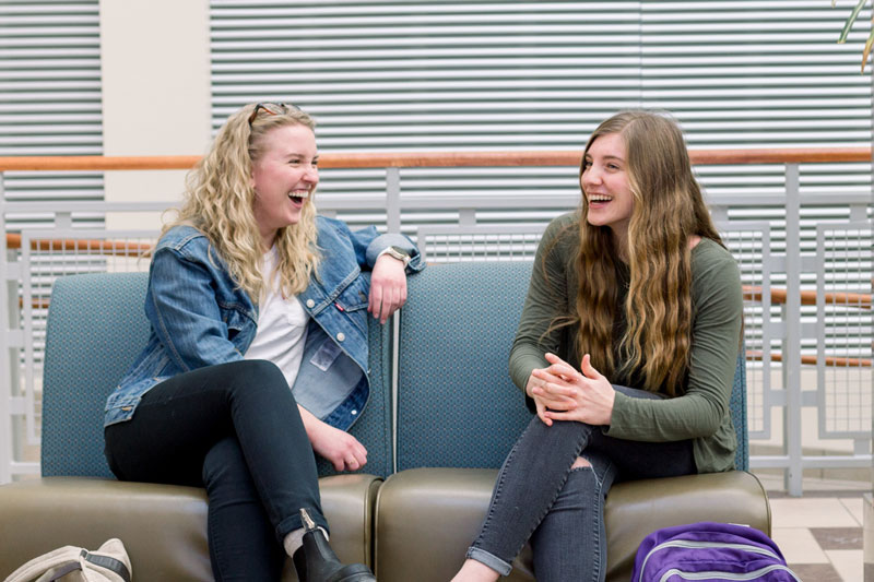 Two female students laughing in the Euler Atrium