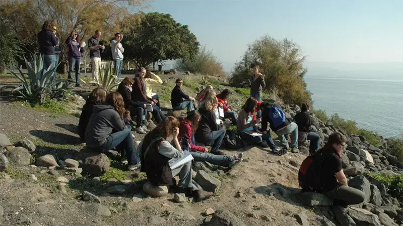 Taylor students sitting on a cliffside overlooking the ocean