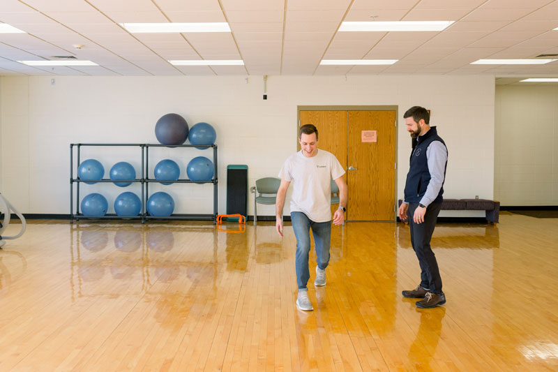 A professor watching a student do lunges