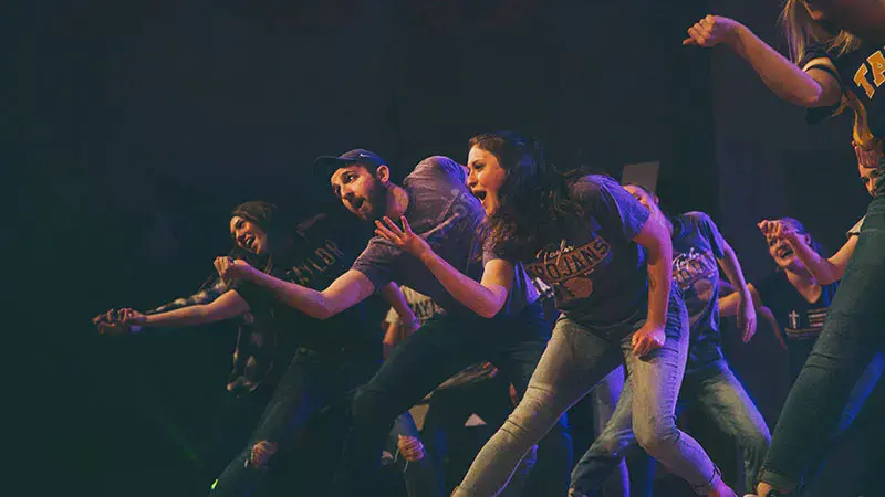 A group a students holding out their right hand in a TU-themed Airband