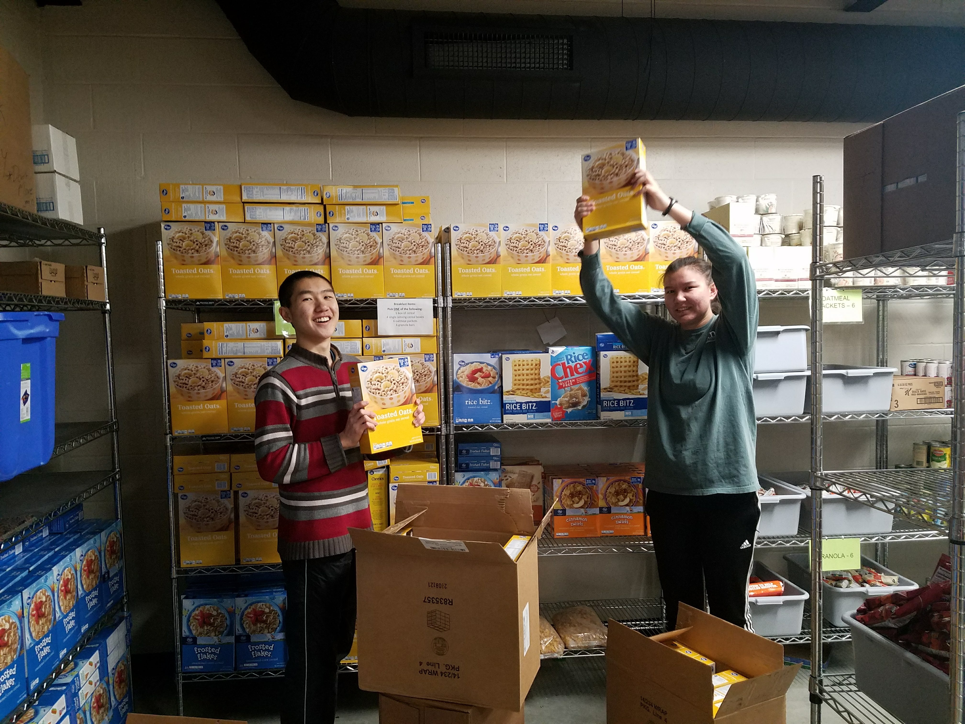 Two students restocking shelves at a food bank