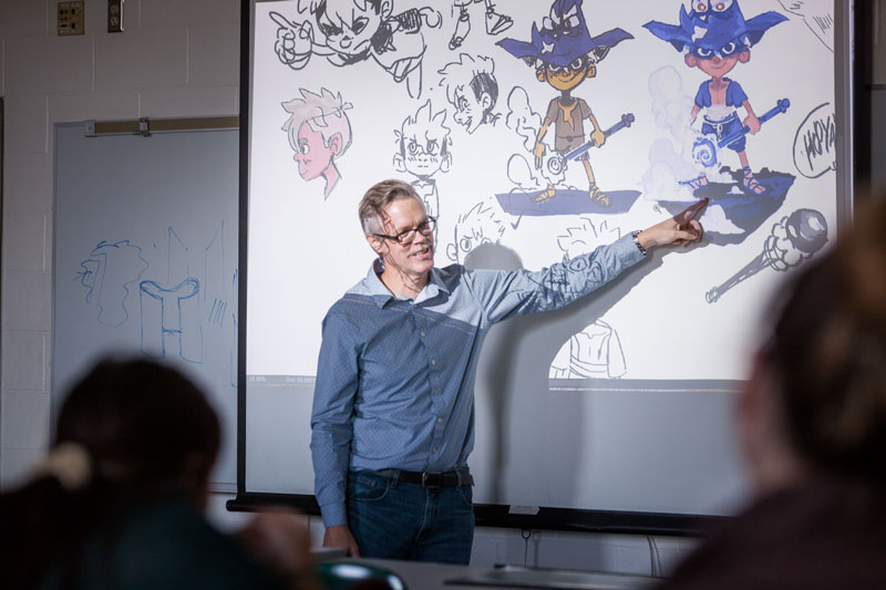 A professor pointing at an illustrated figure on a projector
